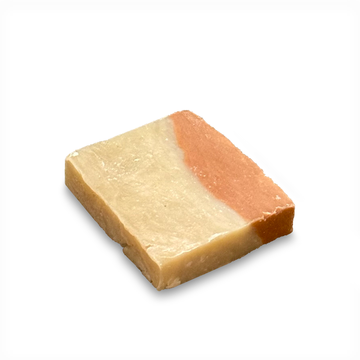 A single rectangular bar of handmade soap with a two-tone design, featuring a light cream-colored lower half and a peachy-orange upper half, isolated on a white background.