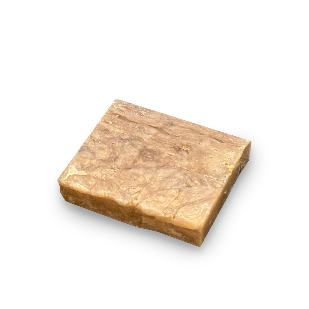 A rectangular bar of soap with a textured, marbled surface in shades of light brown and beige, shown on a plain white background.