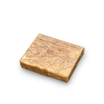 A rectangular bar of soap with a textured, marbled surface in shades of light brown and beige, shown on a plain white background.