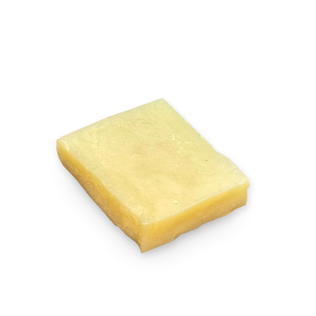 A single square block of pale yellow wax or beeswax, shown on a plain white background.