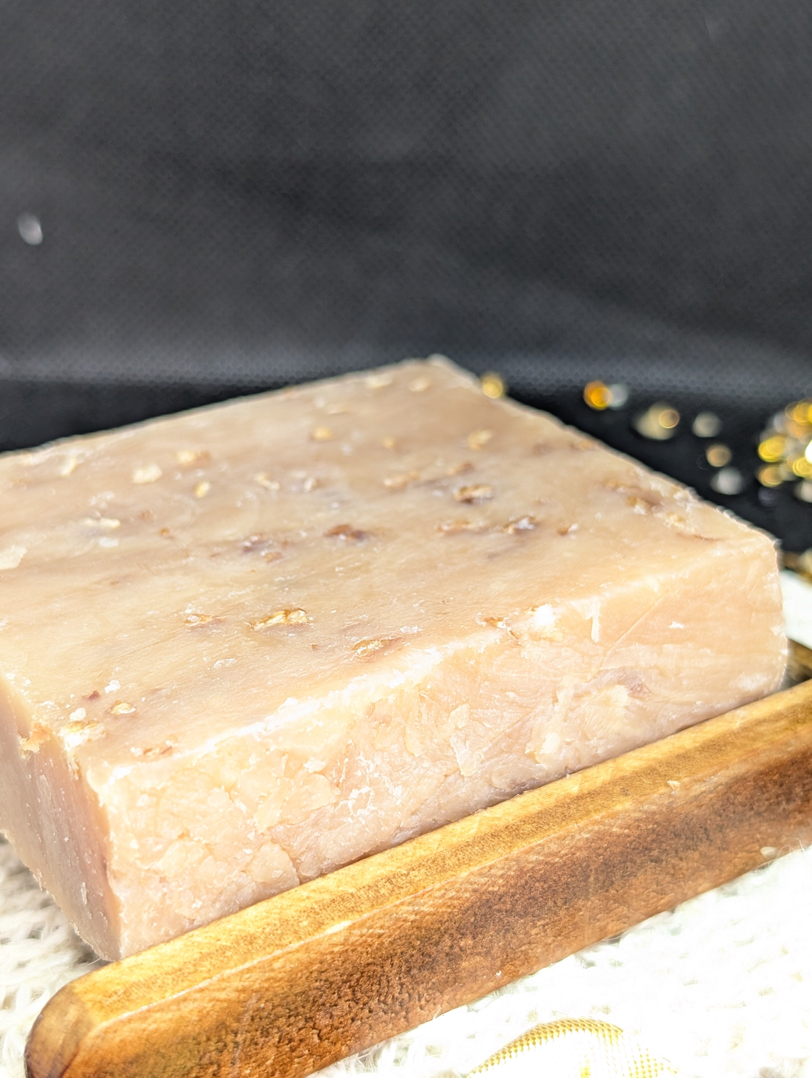 Organic honey oatmeal soap bar with visible exfoliating oatmeal on a wooden soap rack